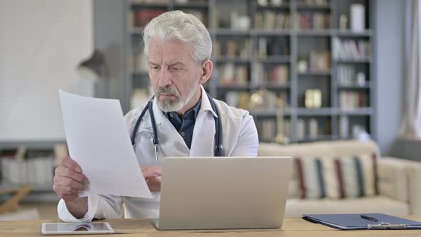 Senior Old Doctor Reading Medical Documents in Clinic alt