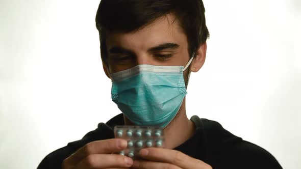 A Portrait of a Young Man in a Medical Mask Reads the Name of the Tablets Get Out and Drink the Pill