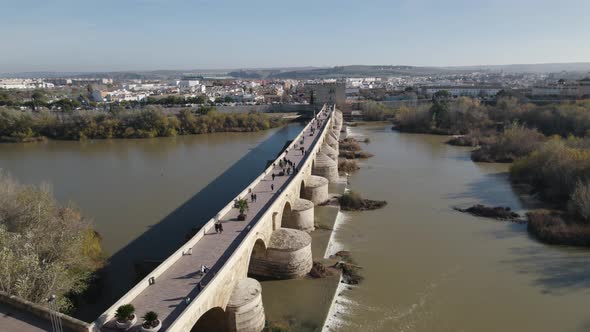 People walking on Cordoba Roman bridge, Spain. Aerial circling