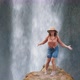 A Young Woman Traveler Admires a Waterfall and a Huge Stream of Water in Delight - VideoHive Item for Sale