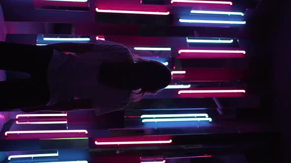 Vertical Video  a View From Behind on the Silhouette of a Woman Standing in Neon Light