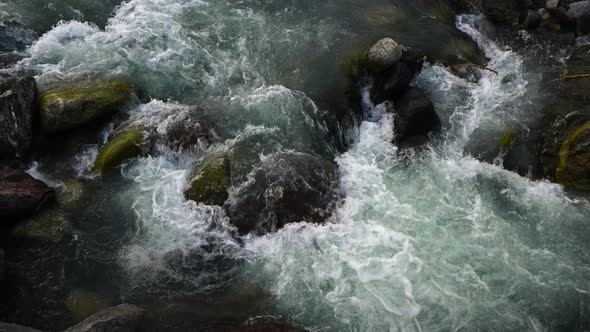 Slow motion of wild clear mountain river , stream flowing through rocks.