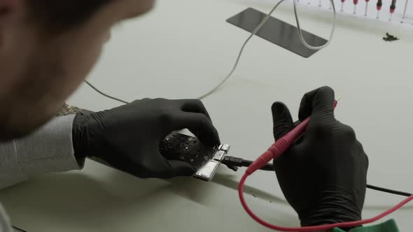 Electronic Renovation in Repair Shop Testing Electric Current in the Motherboard Using Multimeter alt