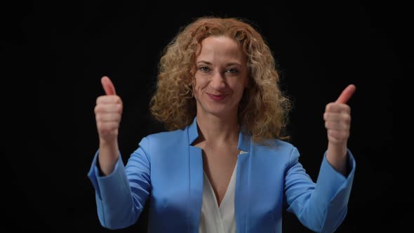 Happy Woman Showing Thumbs Up Posing in Camera Flashes at Black Background alt