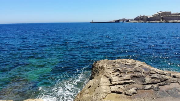 Aerial view towards a fast motor boat sailing in emerald blue sea from Sliema, Malta, Valletta alt
