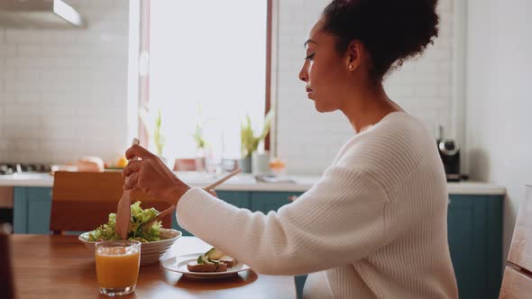 Smiling African pregnant woman tossing salad alt
