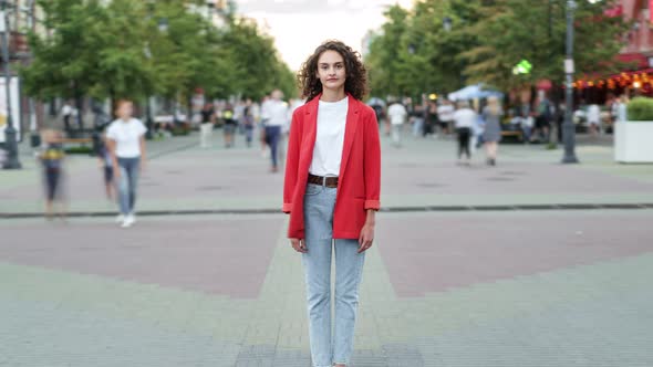 Zoomin Time Lapse of Curlyhaired Girl in Casual Clothing Standing in Busy Street alt