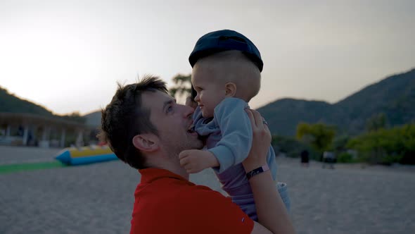 Father Holds Toddler Son Spending Time on Beach at Sunset alt