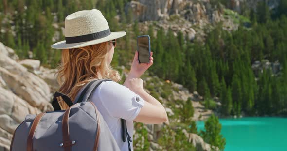 Traveler Woman Takes Pictures on Smartphone of Cinematic Green Lake, Adventure alt