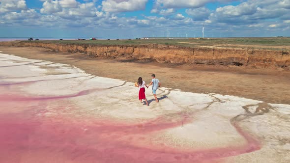 Lovely Young Couple Walking Along Beautiful Pink Lake with Salty Shore alt