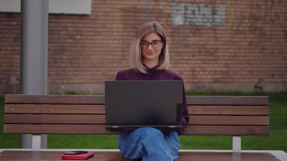 Womvan looking at camera smiling finished tasks on laptop project work alt