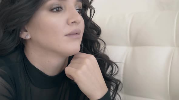 Closeup Pretty Woman with Dark Curly Hair Against Couch alt