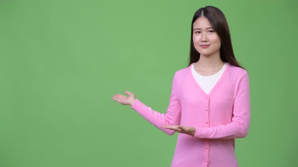 Young Beautiful Asian Woman Showing Something