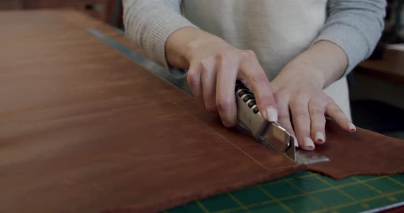 Close Up Shot of Specialist Working with Leather Cuts the Skin for the Product alt