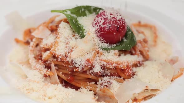 Close-up Sprinkle Grated Tasty Cheese Parmesan To Fresh Appetizing Pasta Dish on Plate at Restaurant