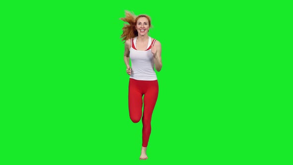 Smiling Sporty Woman Jogging Against Green Screen Background
