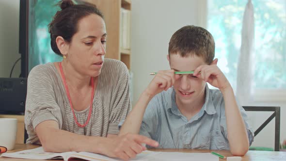 Mother helping her son to do his homework at home alt