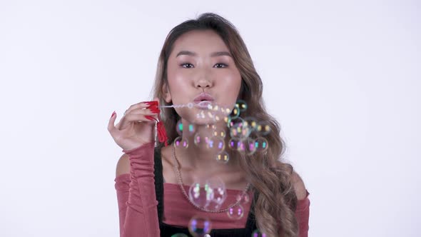 Young Asian Girl Blowing Soap Bubbles