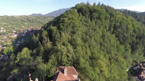 Aerial view of a forested hill and Bran Castle
