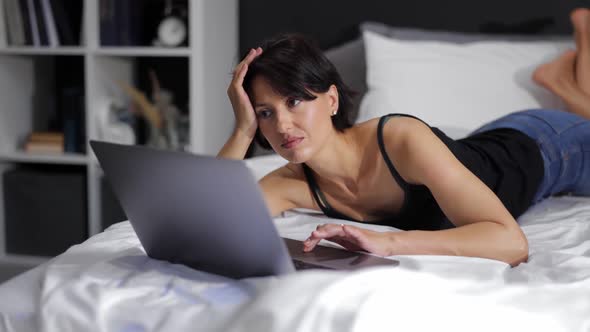Woman Lying on Bed with Laptop