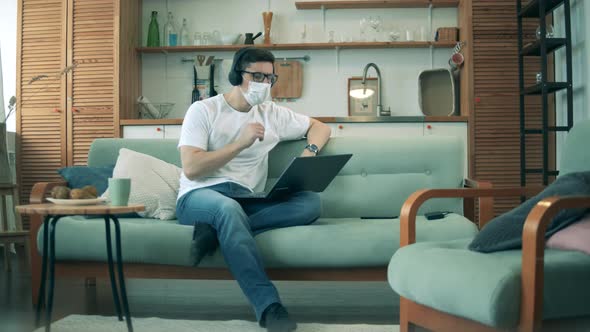 A Man on Self-isolation Is Operating a Laptop in the Living Room. Man Work at Home in Quarantine alt