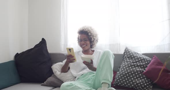 African American Woman Chatting with Mobile Phone on the Sofa at Home