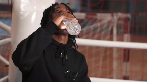 African American Boxer in Hoodies Drink Water From Bottle After Training alt