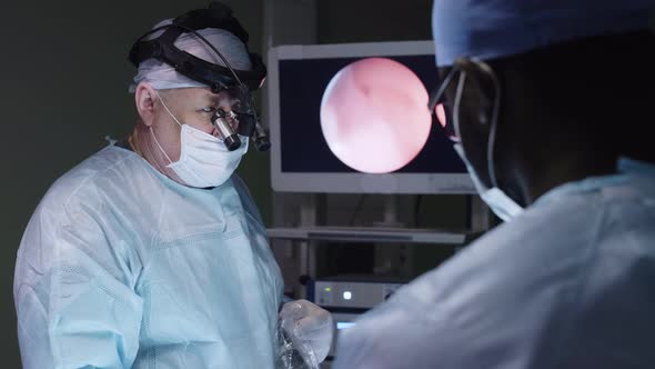 Surgeon with special tool on head performing operation