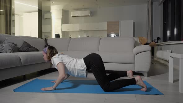 A Girl in Sportswear Does Yoga on a Blue Mat at Home