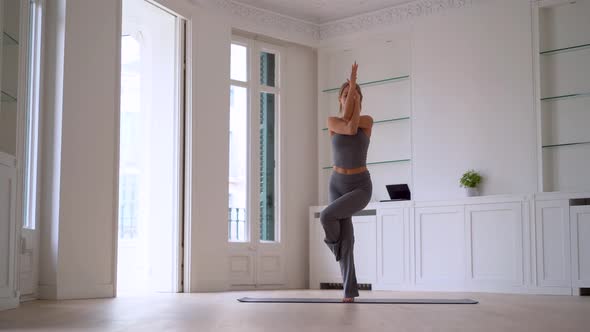 Flexible woman practicing yoga at home alt