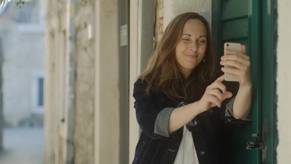 Brunette woman  in sunglasses makes pictures  and selfie by phone in the city. Female wanderlust alt