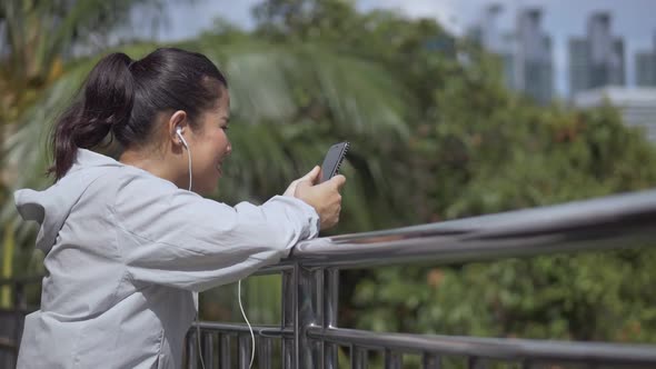 Asian woman fitness runner standing using mobile phone.