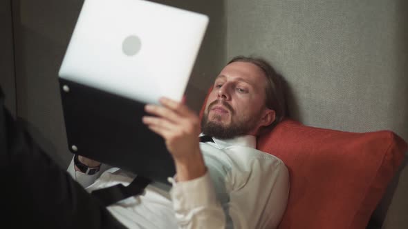 Office Manager Lies in a Large Chair and Works at a Laptop Office Work in an Open Space a Man Types alt