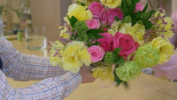 A Young Man is Served a Unique Luxurious Light Composition of Variegated Flowers alt