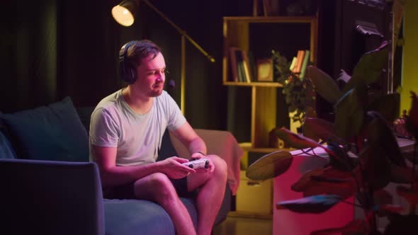 Young Man Gamer Wearing Headphones with Microphone Playing Video Game on Tv Gesturing alt