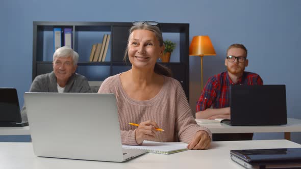 Adult Students in Class Listening To Teacher and Writing Down Notes alt