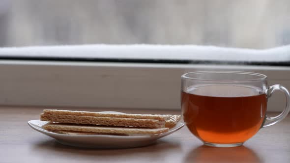 A Large Mug of Tea and Diet Bread in a Plate on the Windowsill in Winter