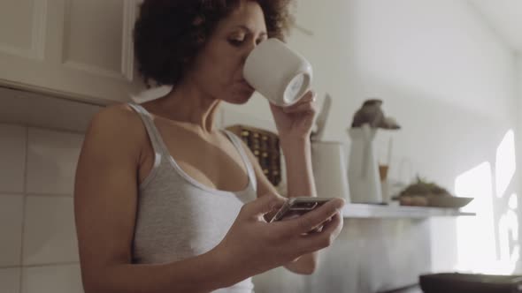 Afro American woman in kitchen enjoying coffee in the morning