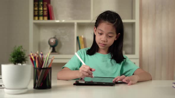 Asian kid girl drawing and painting cartoons on tablet computer, little child using digital tablet