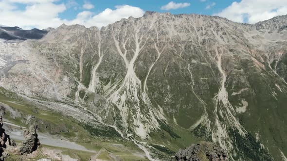 Rocky mountains with clouds among the tops of the rocky hills and blue sky alt