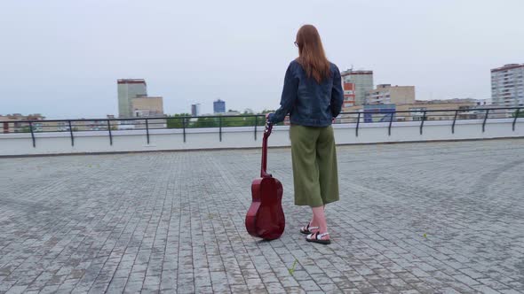 Girl Stands with Classical Guitar in Square