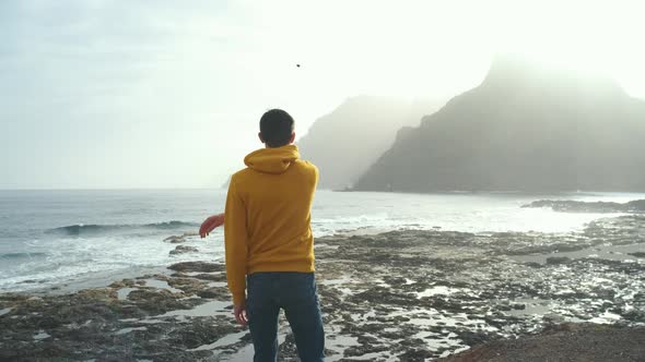 Tourist Man in Yellow Sweatshirt Walks on Volcanic Beach in North of Canary Island Tenerife alt