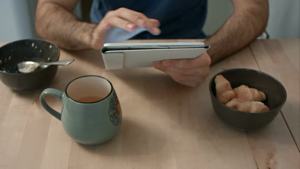 Man's Hands Holding Digital Tablet at Breakfast Table alt