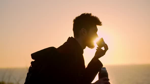 Young Man Drinking Cup Across the Sunrise Slow Motion alt