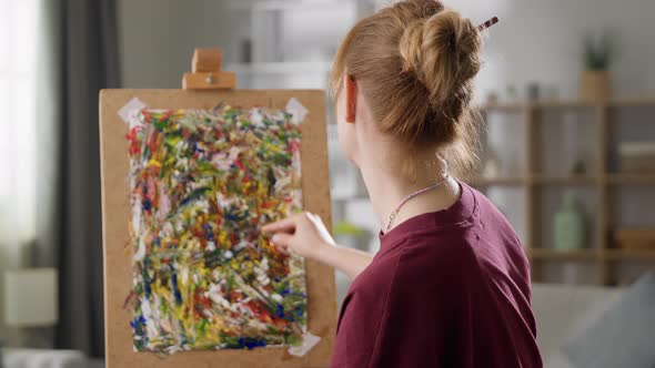 Young Woman Artist Draws a Picture with Oil Paints at Home in the Living Room alt