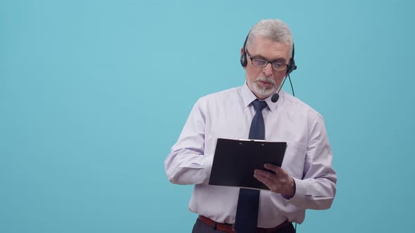 Office Adult Man in a Headset and Suit Speaks and Writes with a Pencil on Paper Tablet in the Studio alt