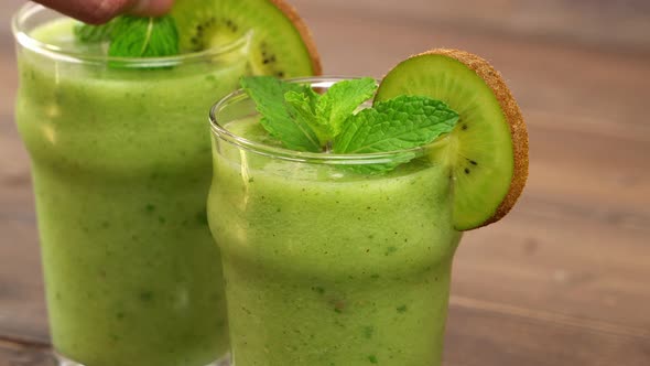 Healthy homemade kiwi fruit smoothies in the glasses being garnished with peppermint leaves
