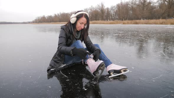 Girl in Mittens Tie Shoelaces at Figure Skates at Ice Rink. alt