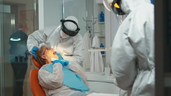 Dentist with Face Shiled Treating Teeth to Senior Woman alt