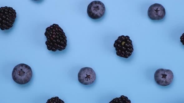Rotating Blackberries and Blueberries on a Blue Background Closeup Top View